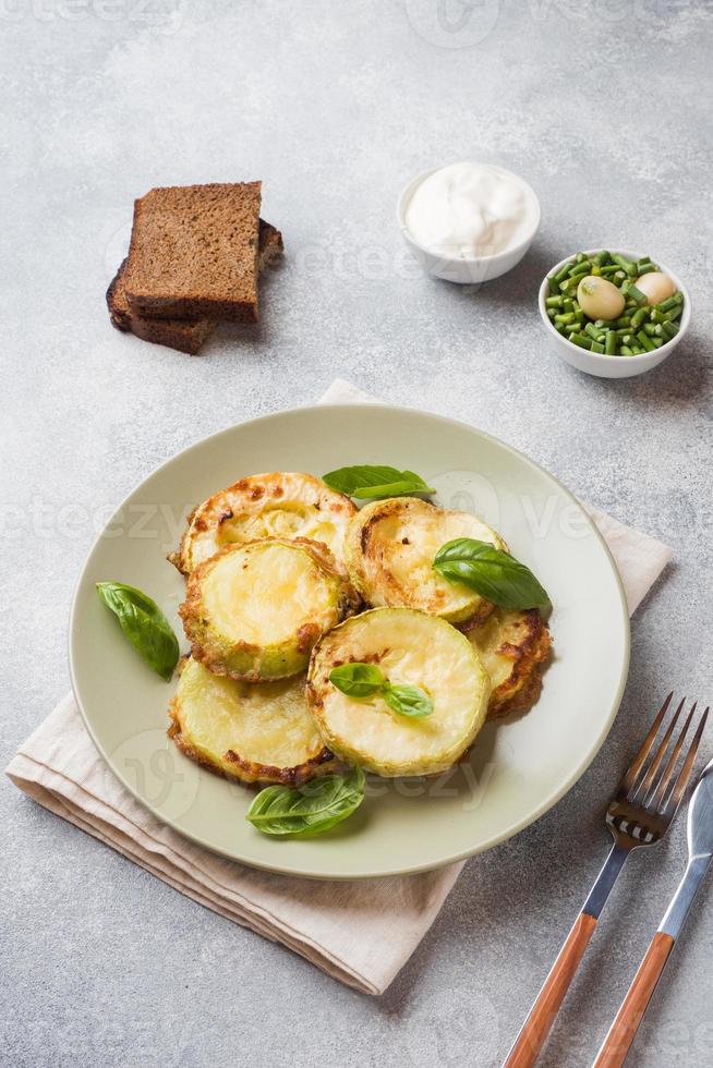 fette di fritte zucchine nel pastella con aglio e basilico su un' piatto. foto