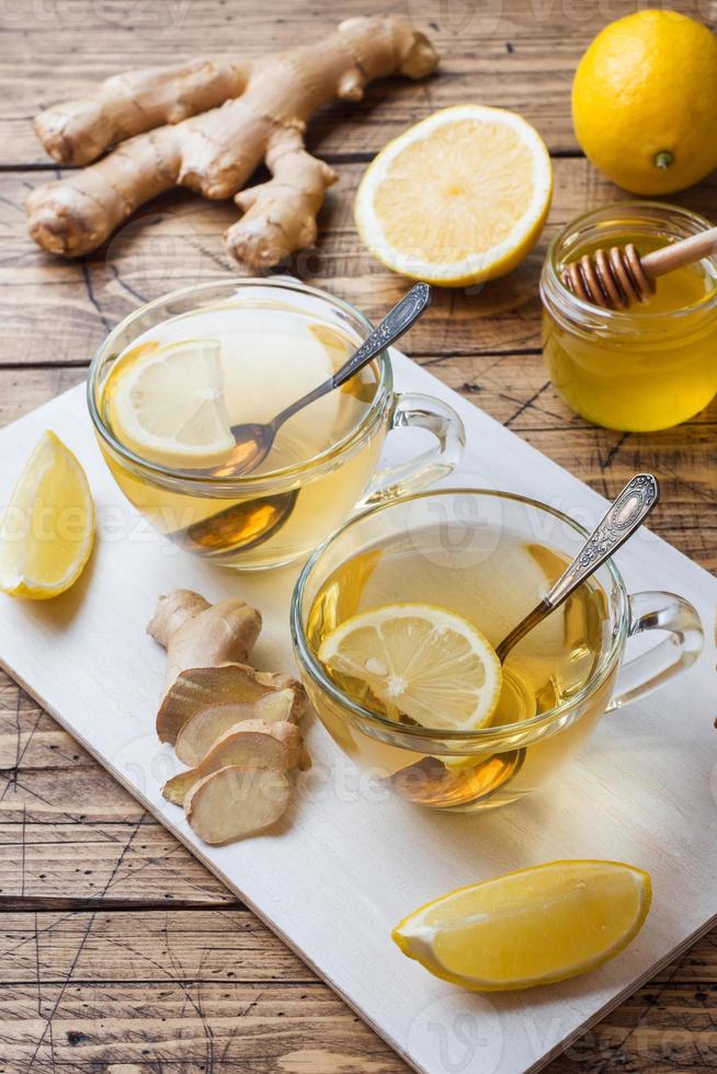 Due tazze di naturale erbaceo tè Zenzero Limone e miele su un' di legno sfondo. foto