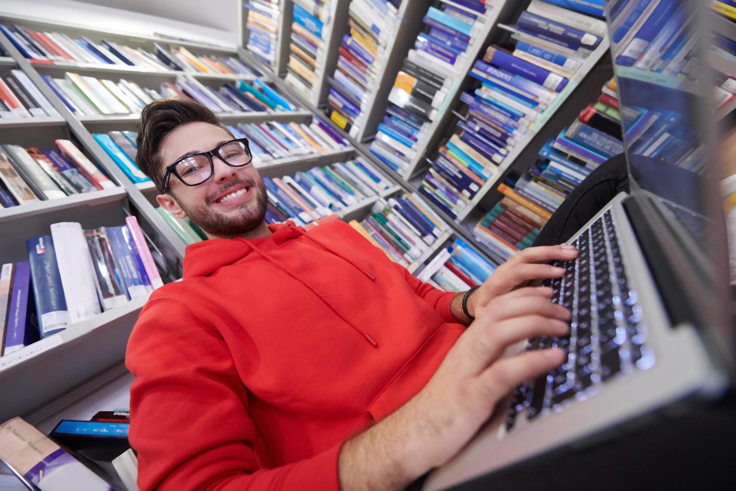 il studenti usi un' taccuino, il computer portatile e un' scuola biblioteca foto