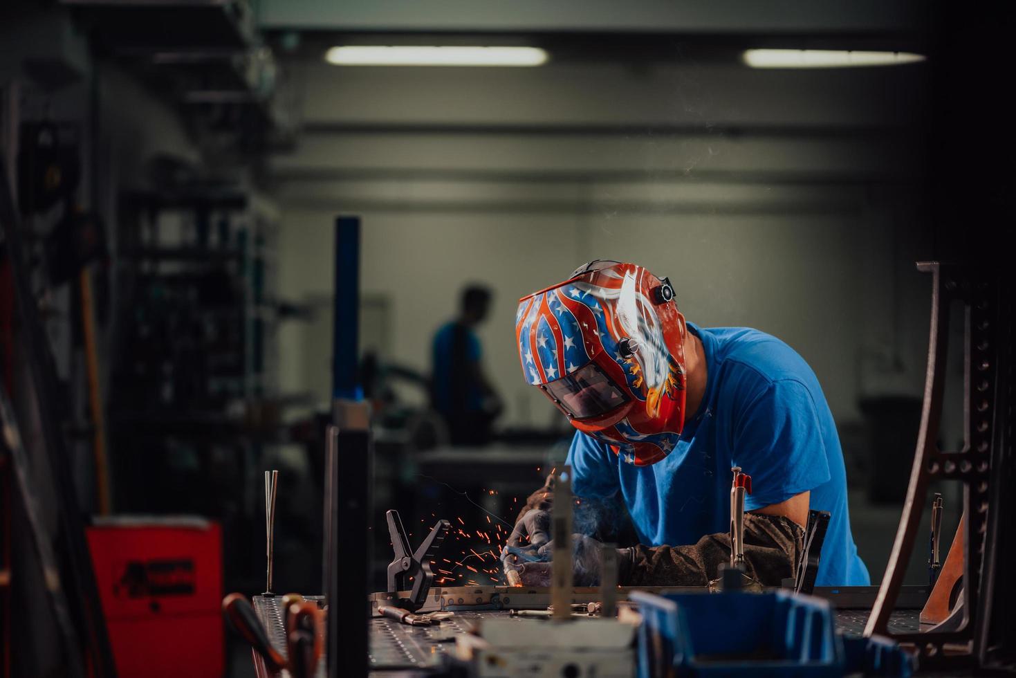 saldatore professionista dell'industria pesante che lavora all'interno della fabbrica, indossa il casco e inizia a saldare. messa a fuoco selettiva foto