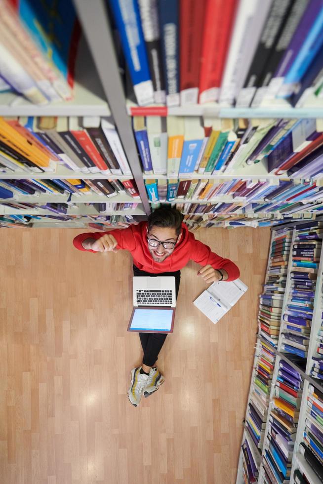 il studenti usi un' taccuino, il computer portatile e un' scuola biblioteca foto