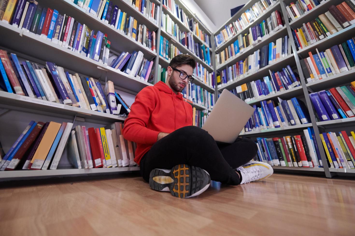 il studenti usi un' taccuino, il computer portatile e un' scuola biblioteca foto