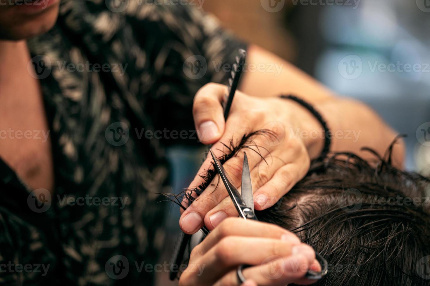 barbiere. avvicinamento di uomo taglio di capelli, maestro fa il capelli messa in piega nel barbiere negozio. avvicinamento, maestro barbiere fa il acconciatura e messa in piega con forbici. concetto barbiere. foto