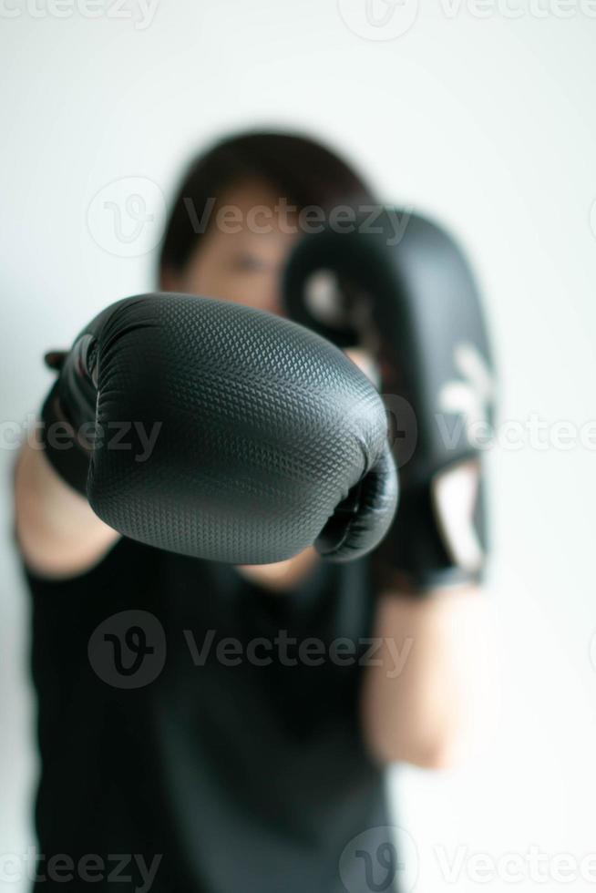 un' donna nel nero boxe guanti allungamento sua giusto cazzotto per il davanti obbiettivo. foto