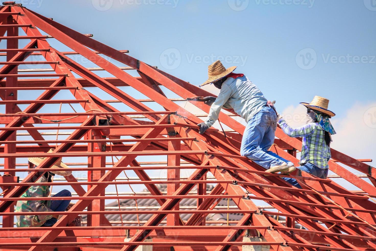 lavoratori del saldatore che installano la struttura del telaio in acciaio del tetto della casa in un cantiere edile foto