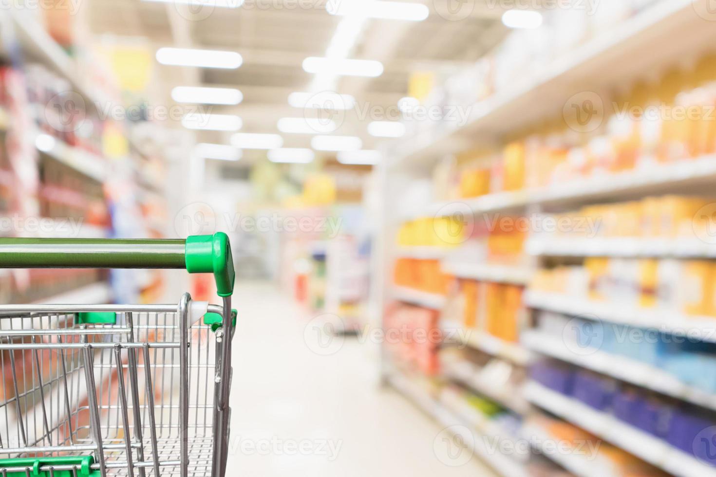 carrello della spesa verde vuoto del supermercato con sfondo sfocato del corridoio del negozio di alimentari della sfocatura astratta foto