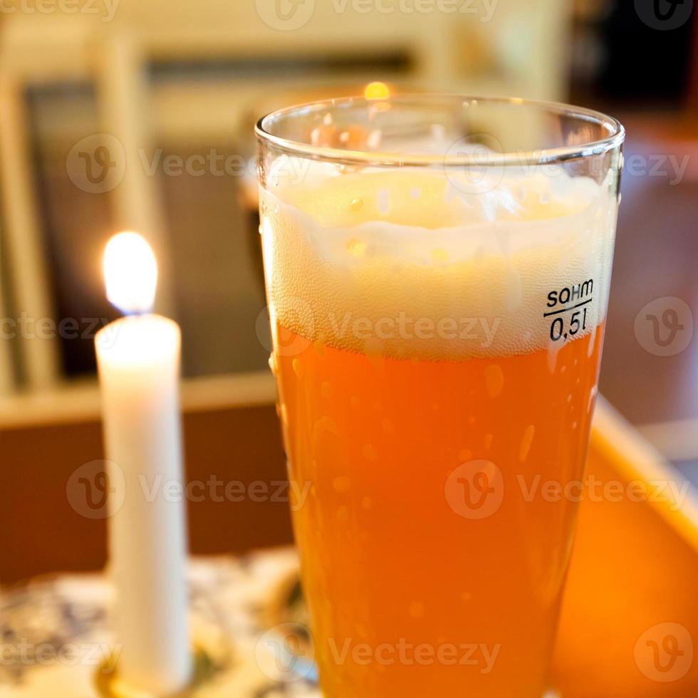 bicchiere di birra e illuminato candela su tavolo foto