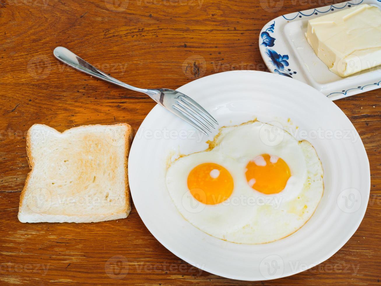 prima colazione con Due fritte uova nel bianca piatto foto