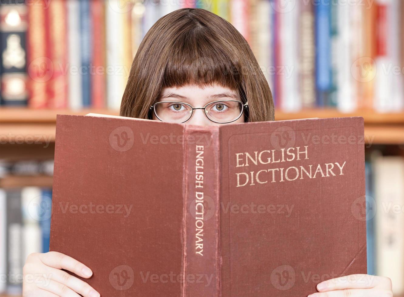 ragazza sembra al di sopra di inglese dizionario e libri foto