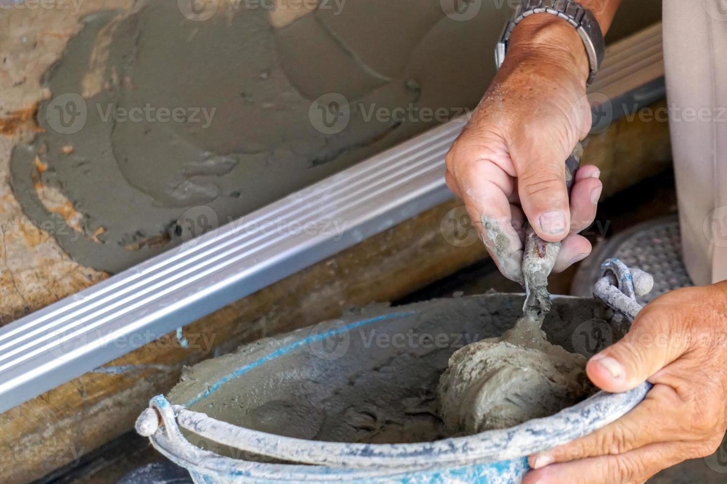 avvicinamento mani di lavoratore Tenere legna cazzuola Lavorando a costruzione luogo. foto