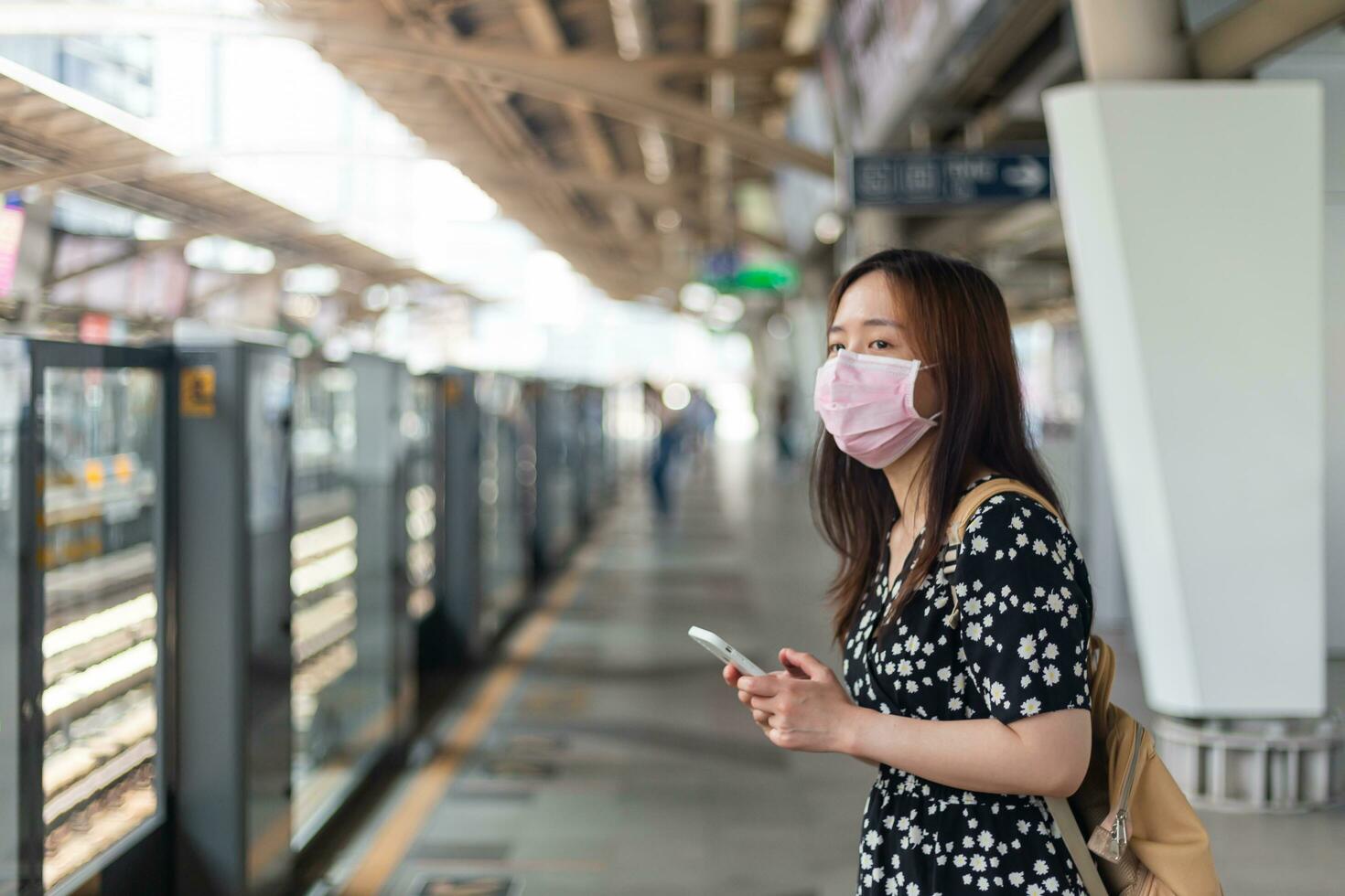 giovane asiatico donna passeggeri in attesa metropolitana treno con città su giorno sfondo con copia spazio. foto