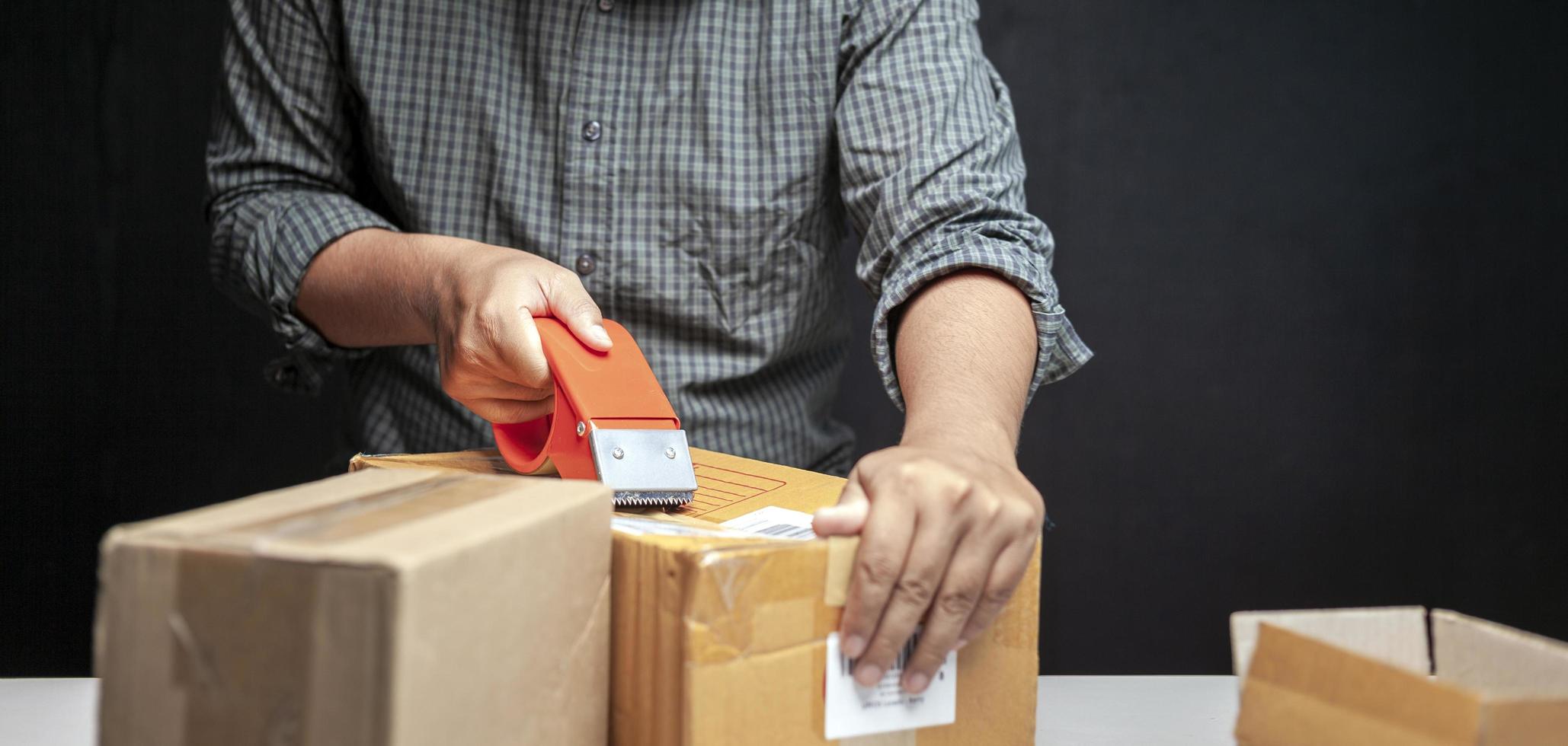 un' uomo è Imballaggio un' piccolo scatola di il suo in linea attività commerciale nel il suo camera a casa. foto