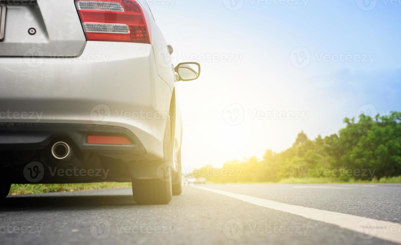 vicino su indietro di argento auto e leggero su il strada foto