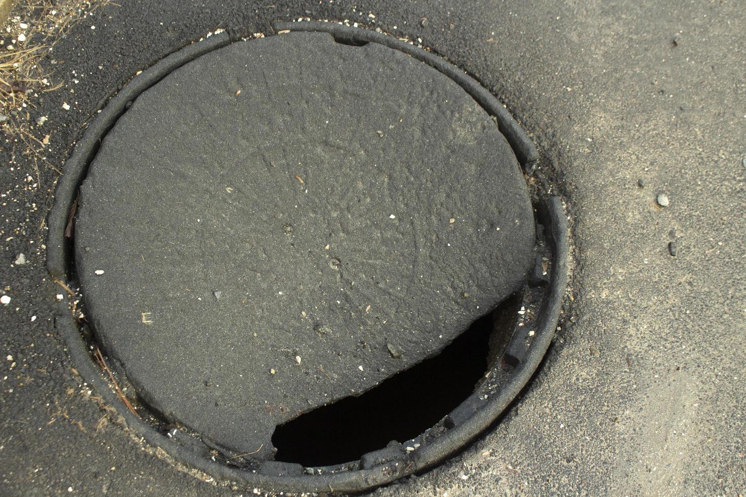 buco nel asfalto. schiudere nel terra. rotto coperchio. pericoloso posto su strada. foto