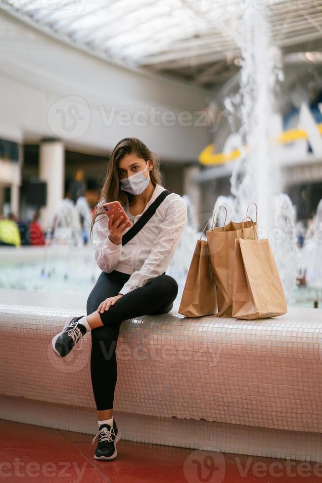 donna utilizzando smartphone interno. sms e comunicare nel centro commerciale foto