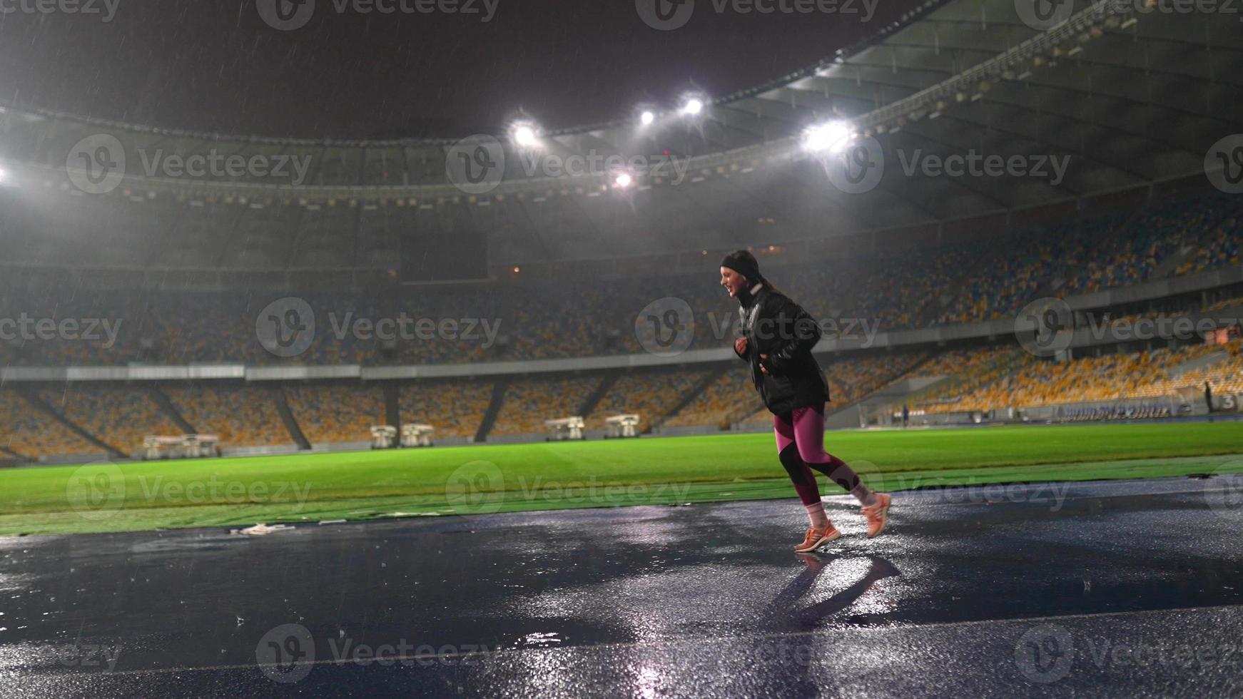 persone partire nel per gli sport a notte stadio nel piovoso tempo metereologico foto