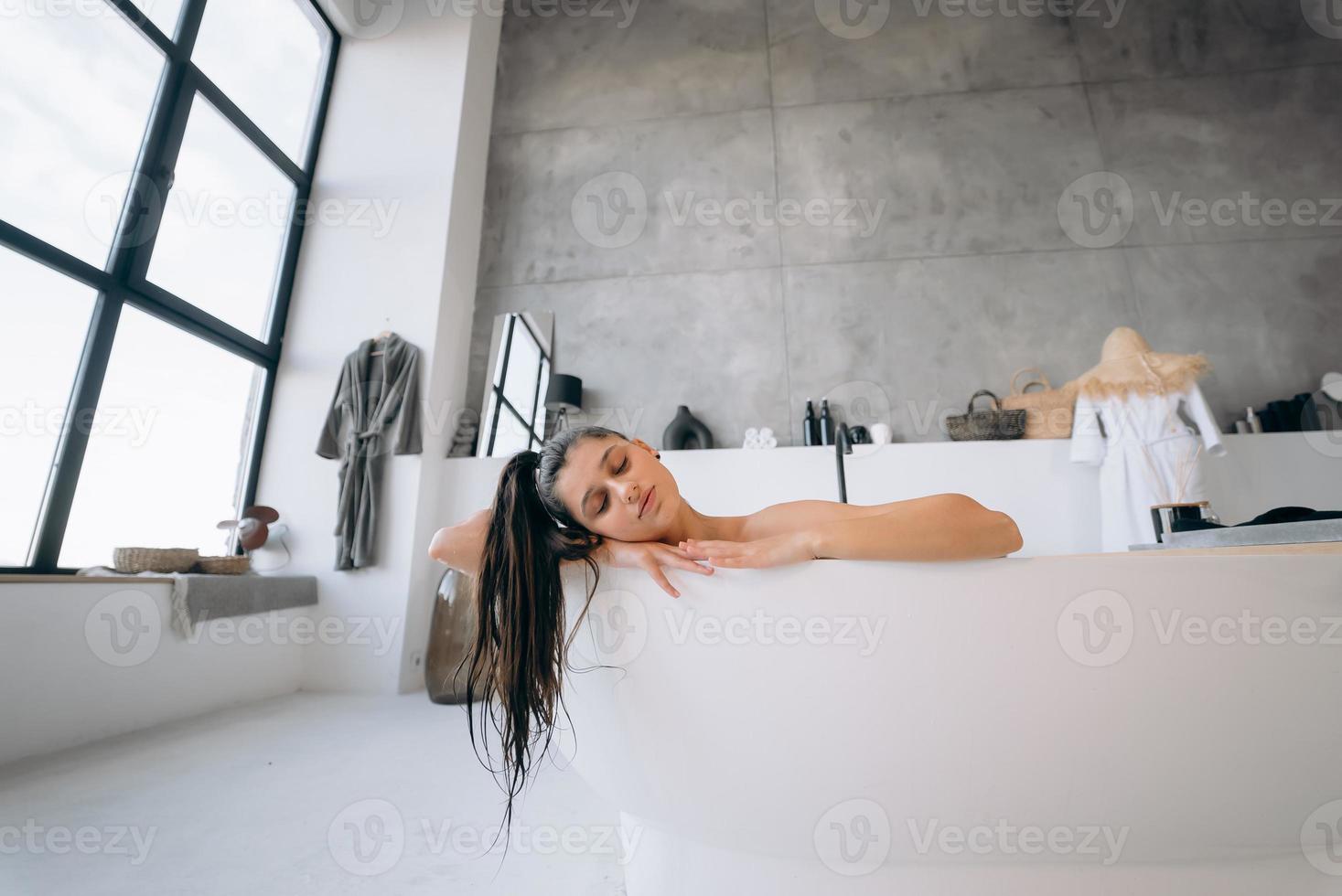 rilassato signora assunzione bagno, godendo e rilassante mentre dire bugie nel vasca da bagno foto