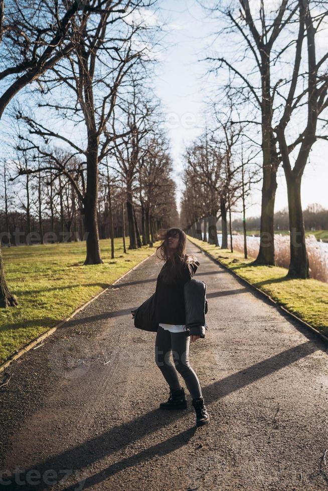 ritratto di un' brunetta ragazza avendo divertimento nel un' parco nel il raggi di il luminosa sole. foto