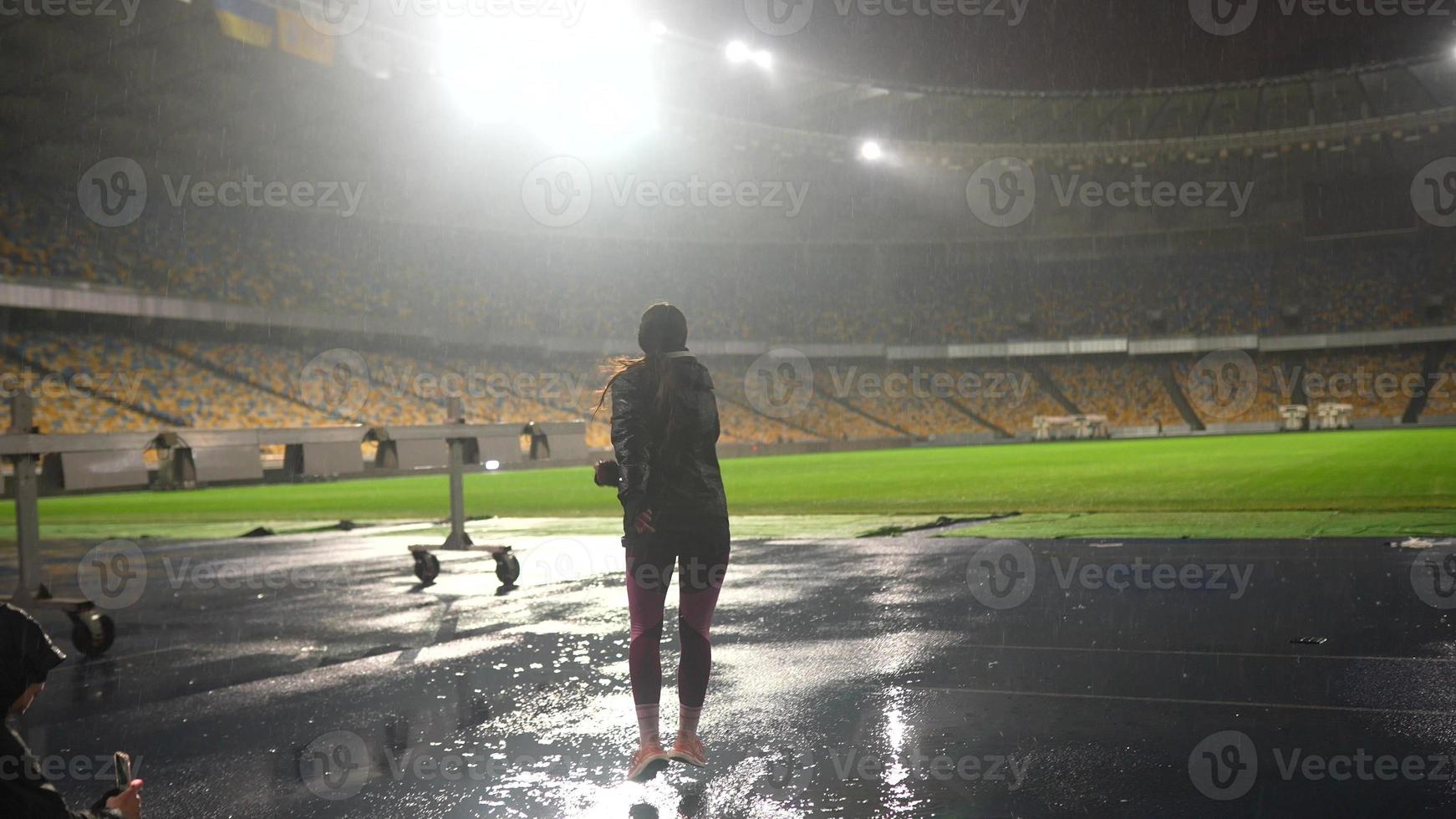 persone partire nel per gli sport a notte stadio nel piovoso tempo metereologico foto