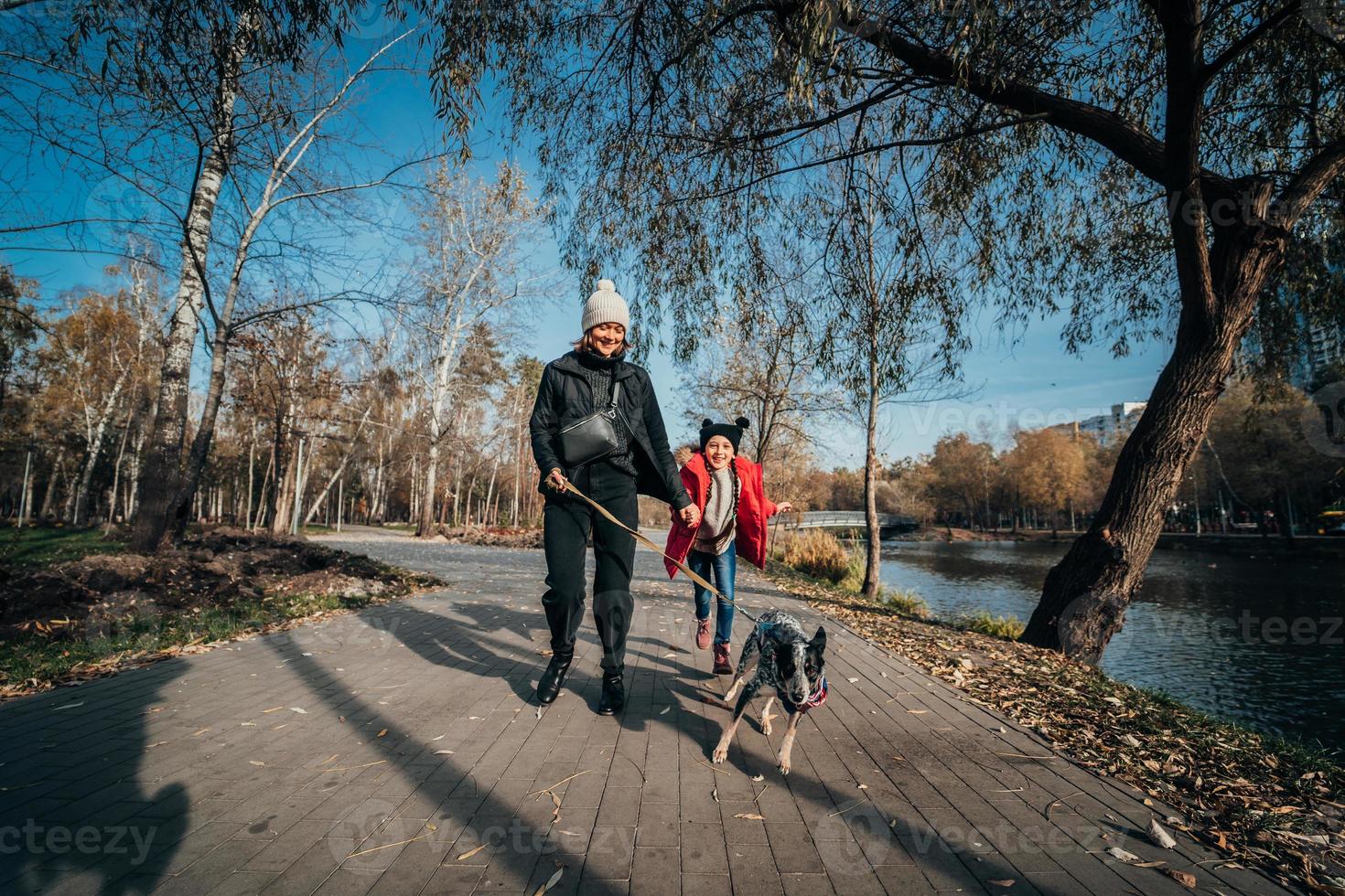 contento madre e sua figlia camminare con cane nel autunno parco foto