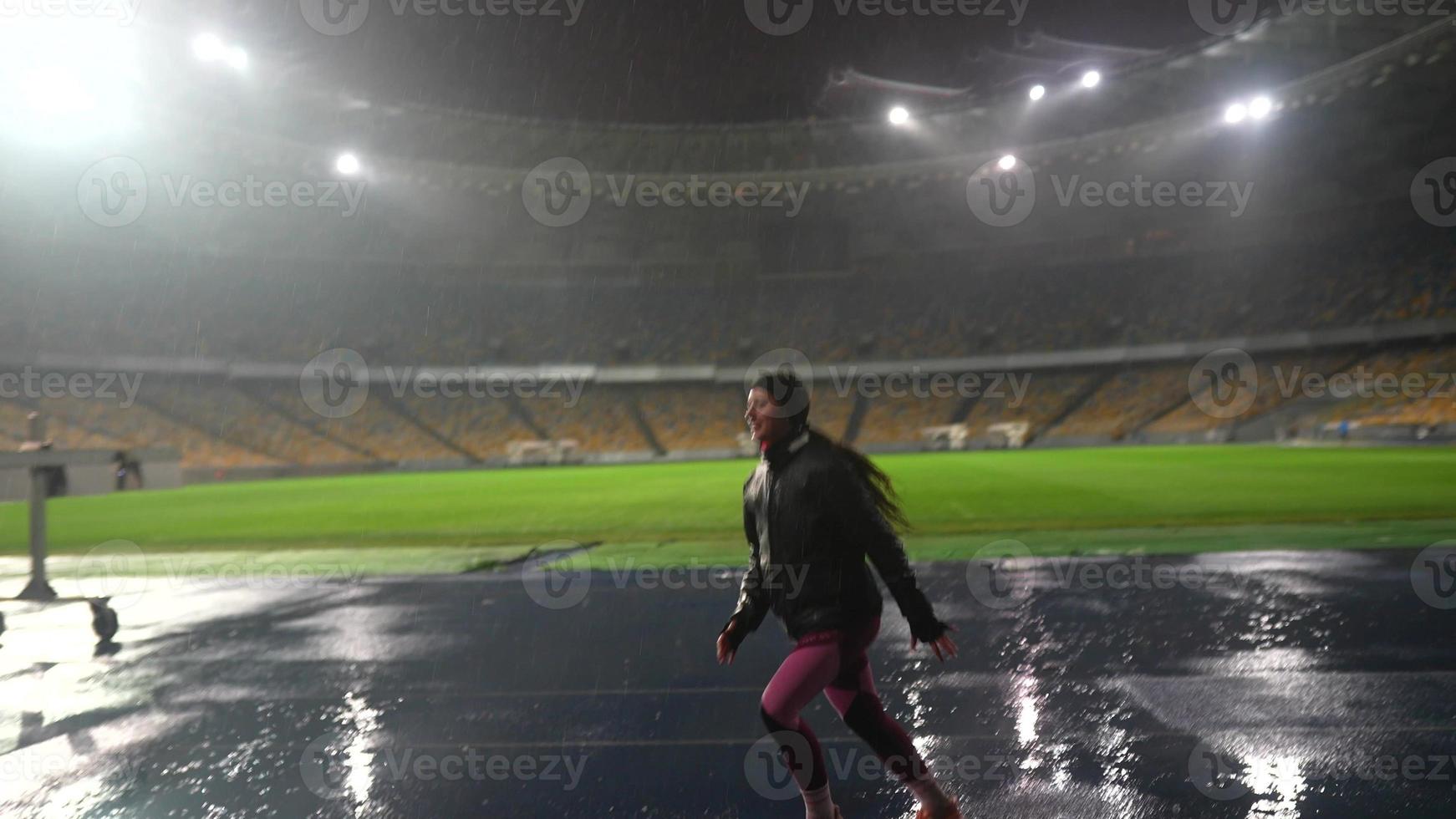 persone partire nel per gli sport a notte stadio nel piovoso tempo metereologico foto