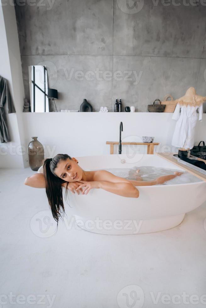 rilassato signora assunzione bagno, godendo e rilassante mentre dire bugie nel vasca da bagno foto