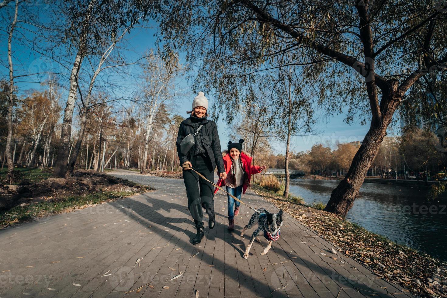 contento madre e sua figlia camminare con cane nel autunno parco foto