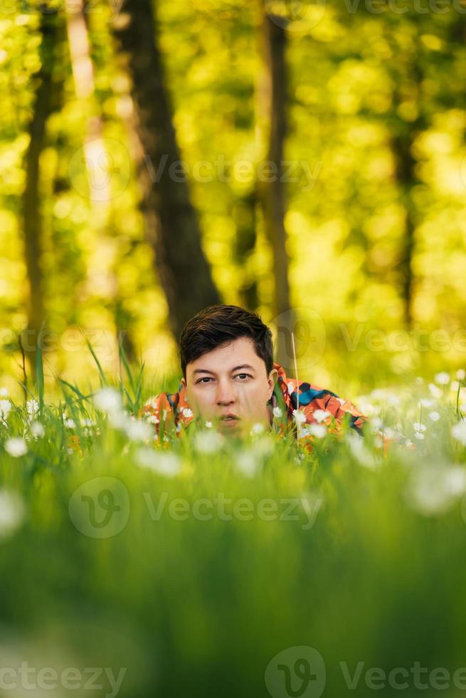 giovane uomo nascondiglio nel il verde erba foto