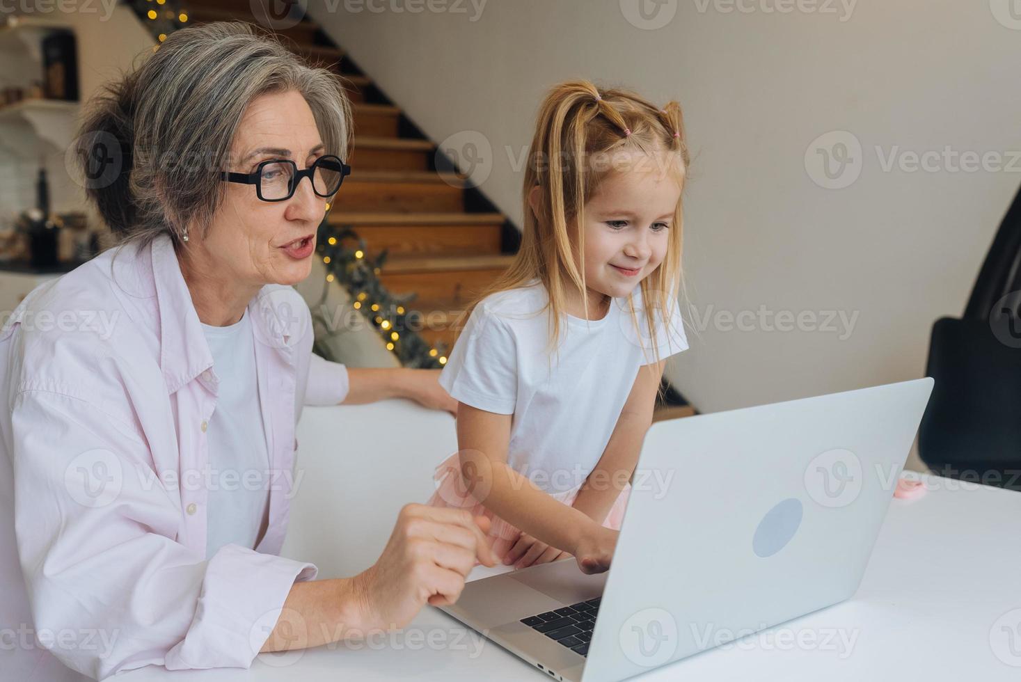 bambino e nonna guardare a il telecamera con il computer portatile foto