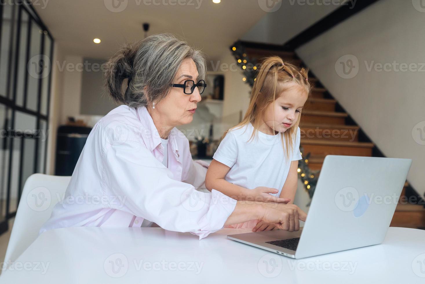 bambino e nonna guardare a il telecamera con il computer portatile foto