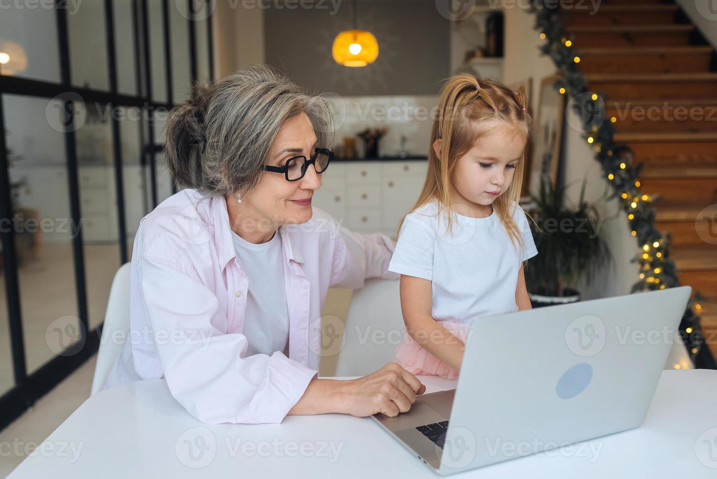 bambino e nonna guardare a il telecamera con il computer portatile foto