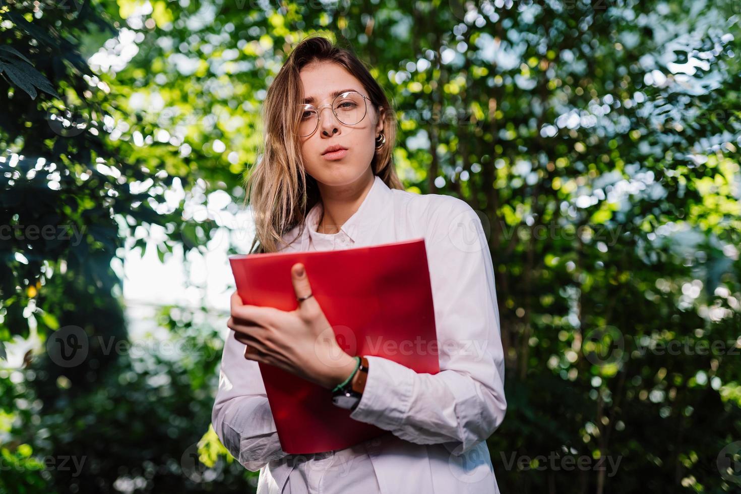 giovane agricolo ingegnere Lavorando nel serra. giovane femmina scienziato guardare a il telecamera foto