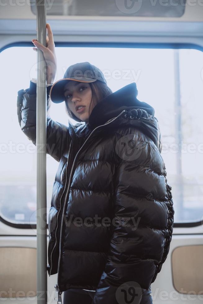 giovane donna sta su il sfondo di un' finestra nel pubblico trasporto foto