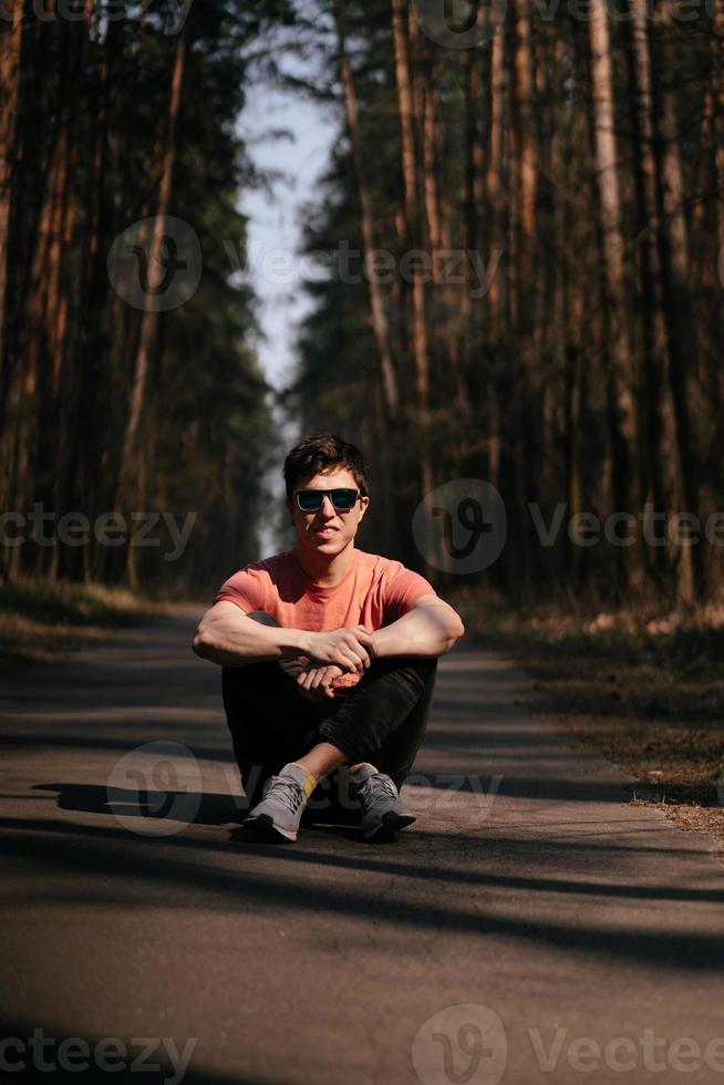 bello giovane uomo nel bianca maglietta e jeans all'aperto nel parco, a piedi nel il parco foto