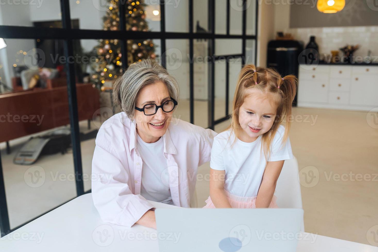 bambino e nonna guardare a il telecamera con il computer portatile foto