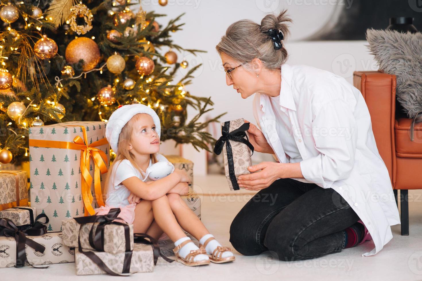 contento nonna dando Natale presente per eccitato nipotina. foto