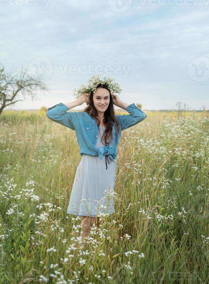 bella ragazza che cammina sul campo in estate con fiori di campo. foto