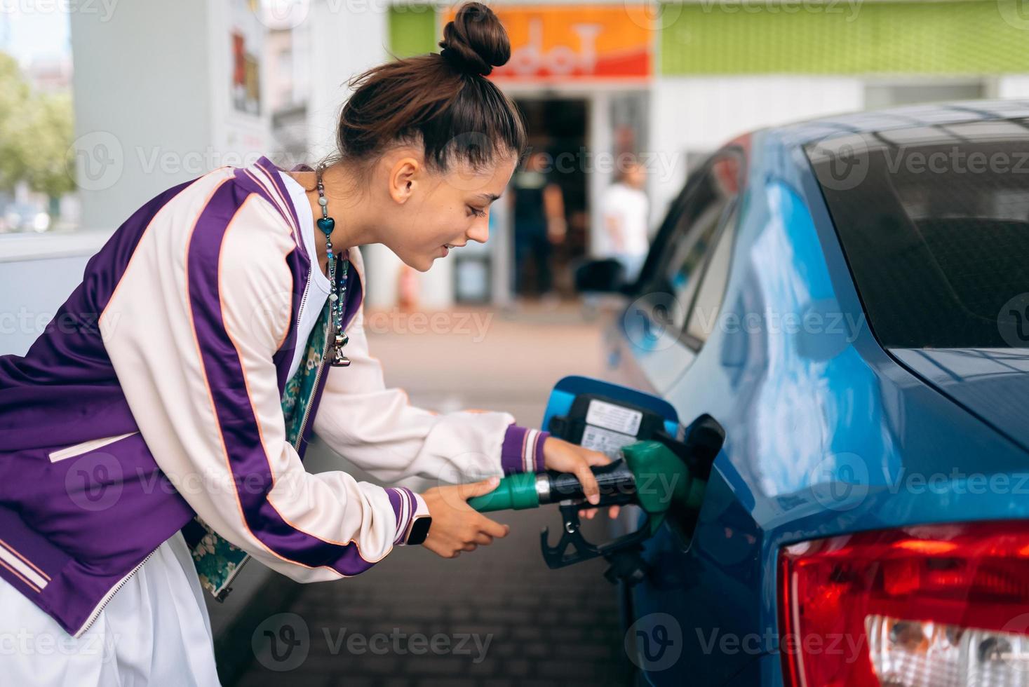 donna Riempimento sua auto con carburante a un' gas stazione foto