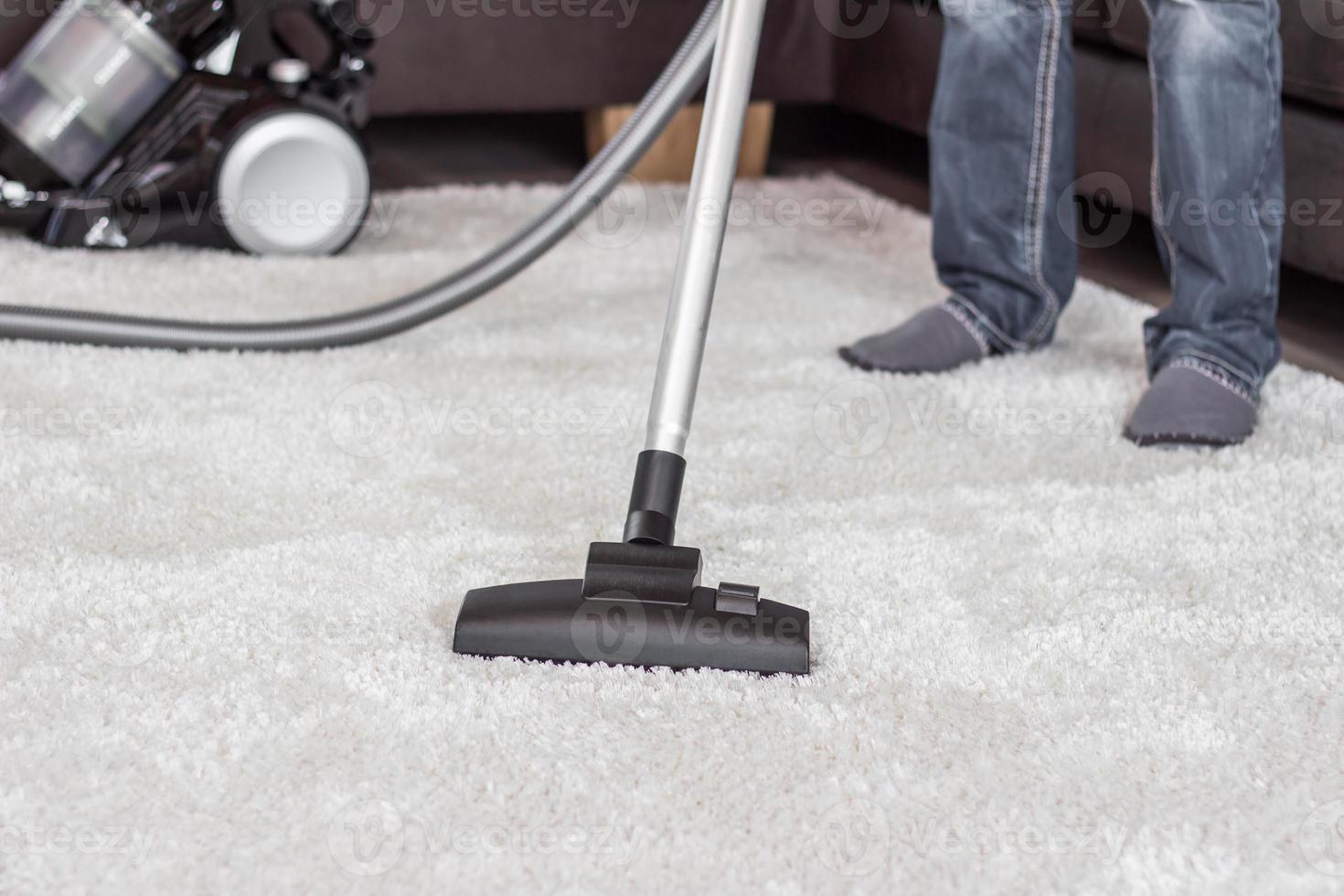 l'uomo pulisce il tappeto con un aspirapolvere foto