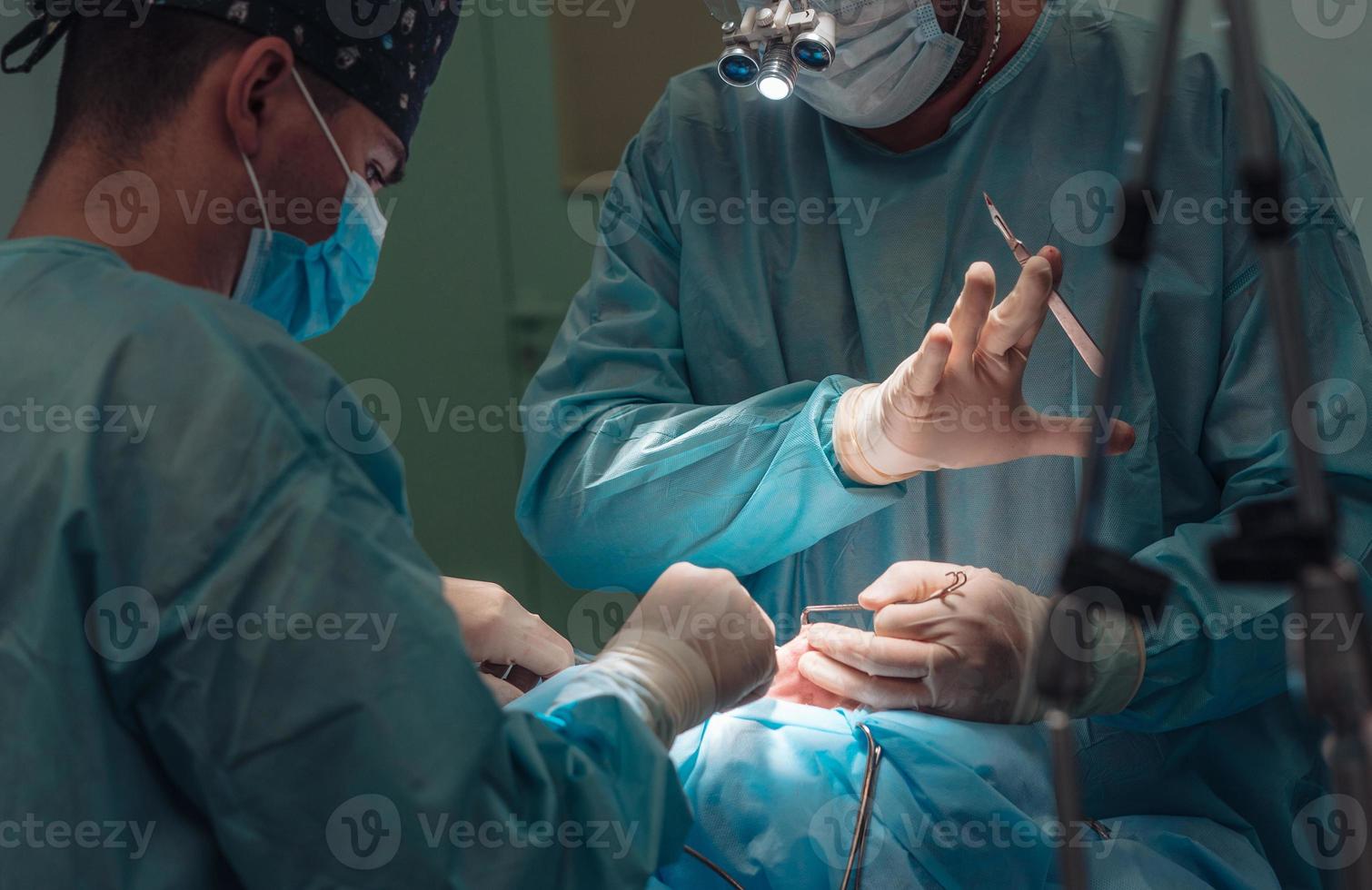 chirurgo e il suo assistente l'esecuzione cosmetico chirurgia su naso foto