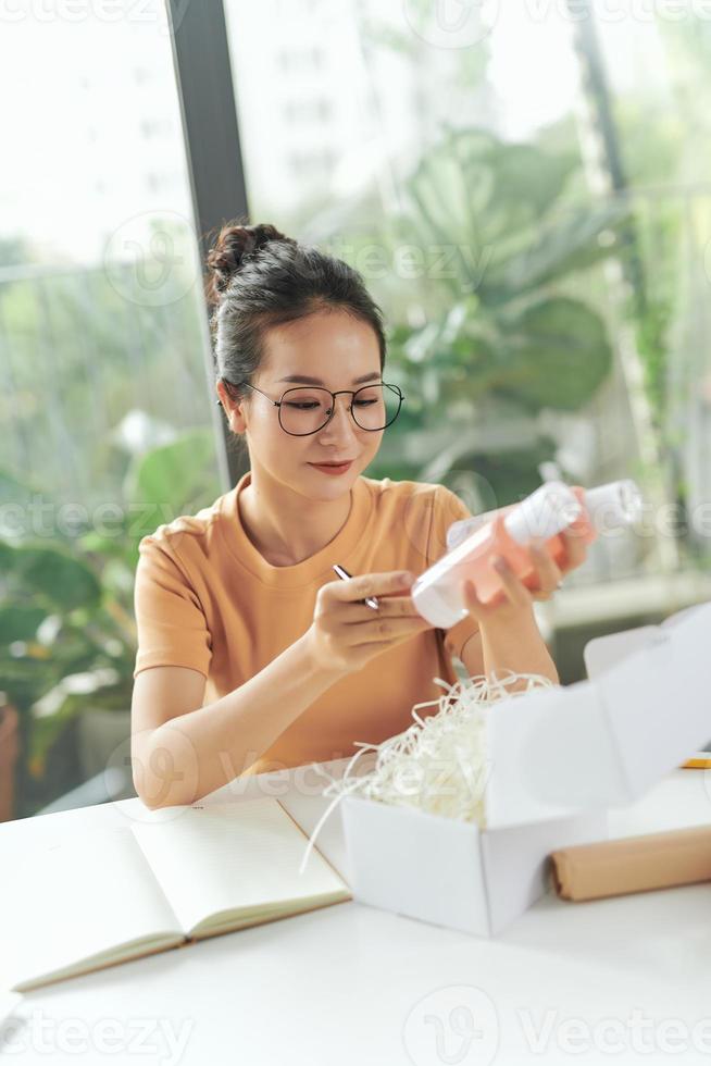 avvicinamento Visualizza di femmina in linea memorizzare piccolo attività commerciale proprietario imprenditore Imballaggio pacchetto inviare spedizione scatola preparazione consegna pacco su tavolo. foto