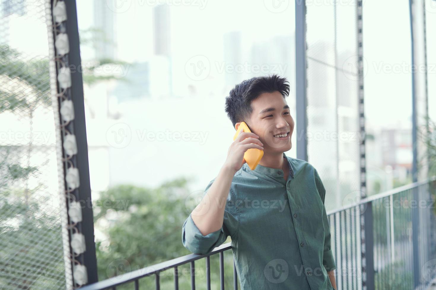 contento uomo A proposito di su cellulare in piedi su balcone nel città nel estate giorno foto