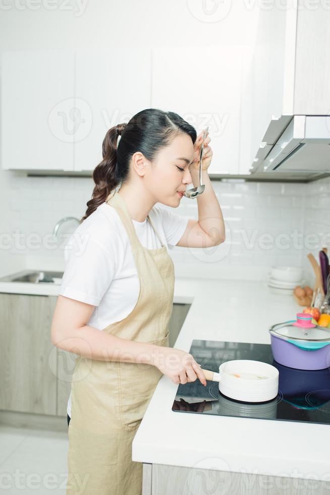 giovane donna in piedi di il stufa nel il cucina . foto