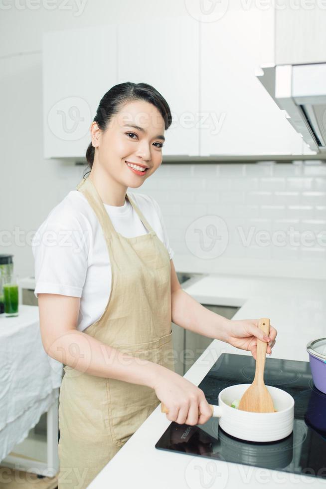 giovane donna in piedi vicino il induzione fornello cucinando pasto nel cucina foto