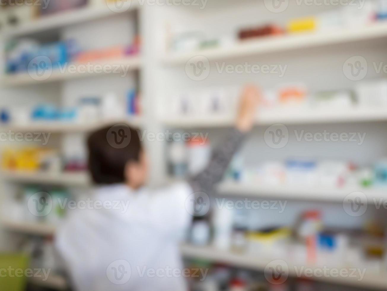 sfocatura farmacista che prende la medicina dallo scaffale in farmacia foto