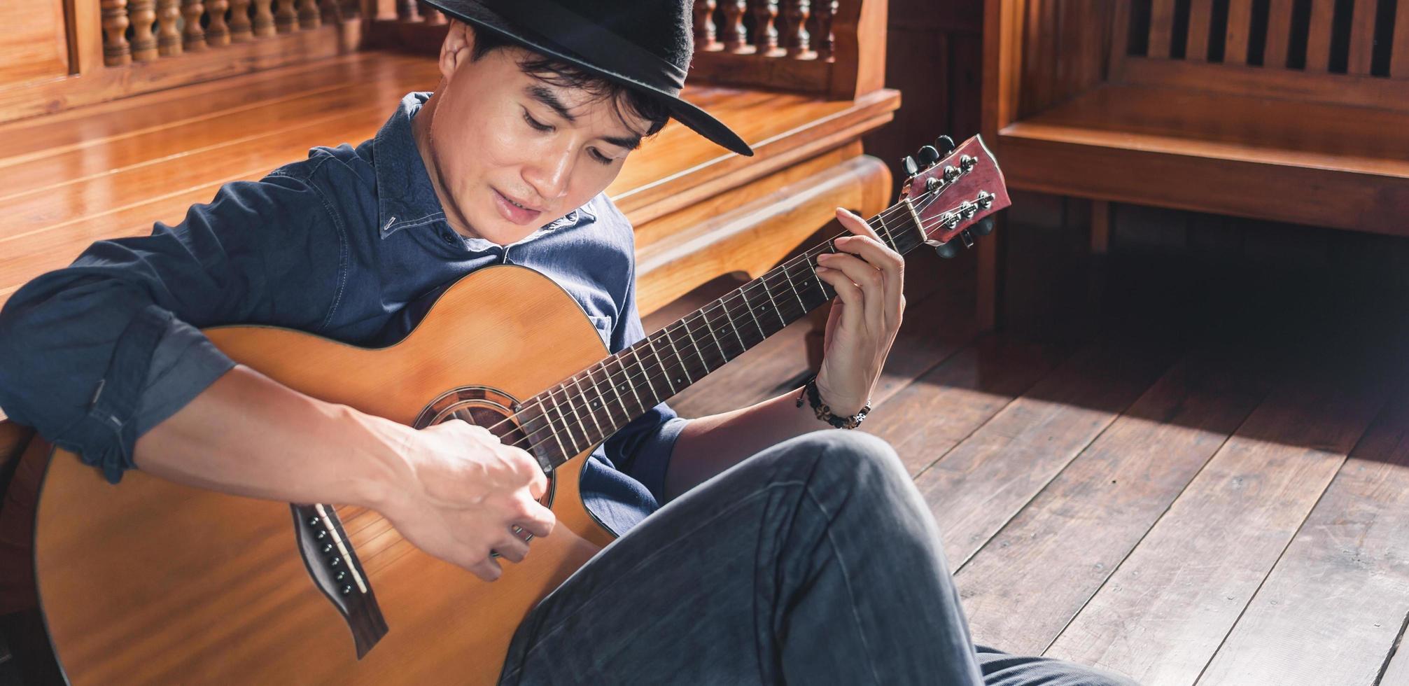 asiatico maschio musicista fricchettone giocando acustico chitarra o praticante chitarra per tempo libero o passatempo passatempo idee per rilassante vacanza a casa. foto