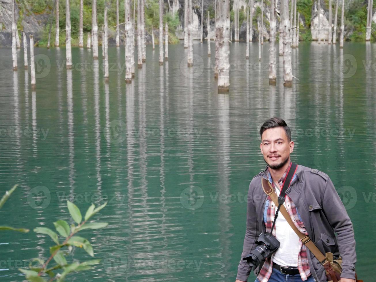 uomo in piedi nel davanti di spoglio tronchi di alberi nel lago kaindy nel Kazakistan foto