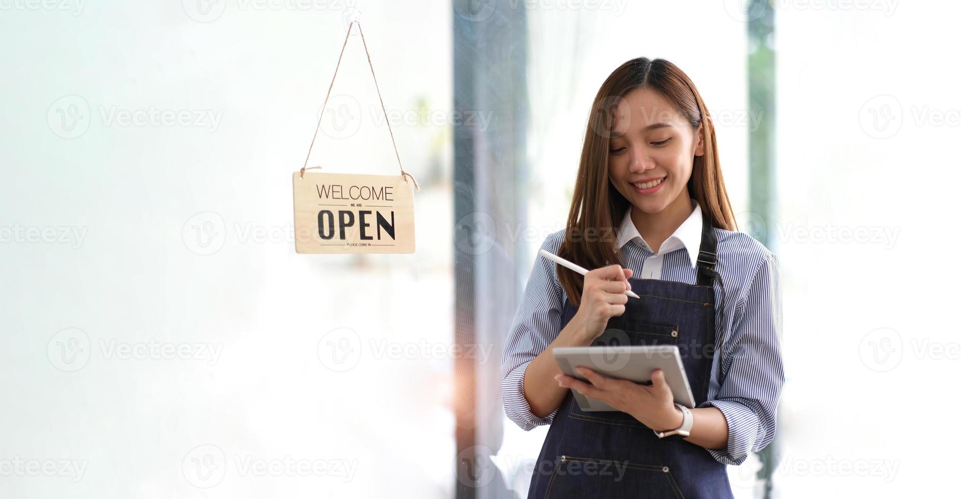 avvio di successo della piccola impresa titolare sme bellezza ragazza stand con tablet smartphone nel ristorante caffetteria. ritratto di donna asiatica abbronzata barista barista proprietario. concetto di business venditore imprenditore PMI foto