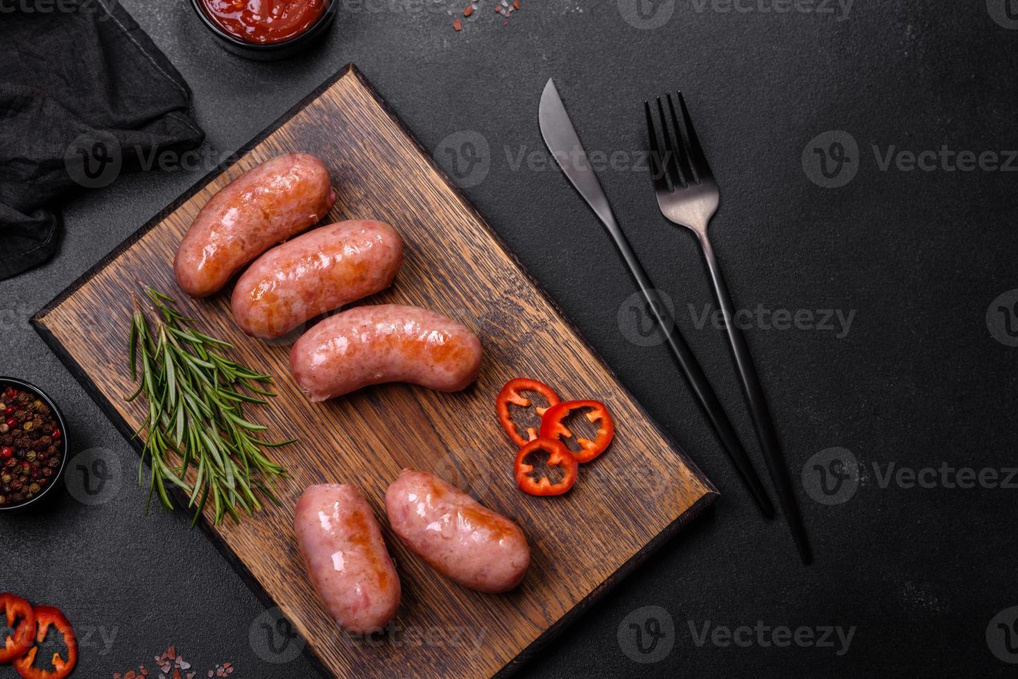 grigliato salsicce con spezie e erbe aromatiche su un' nero sfondo foto