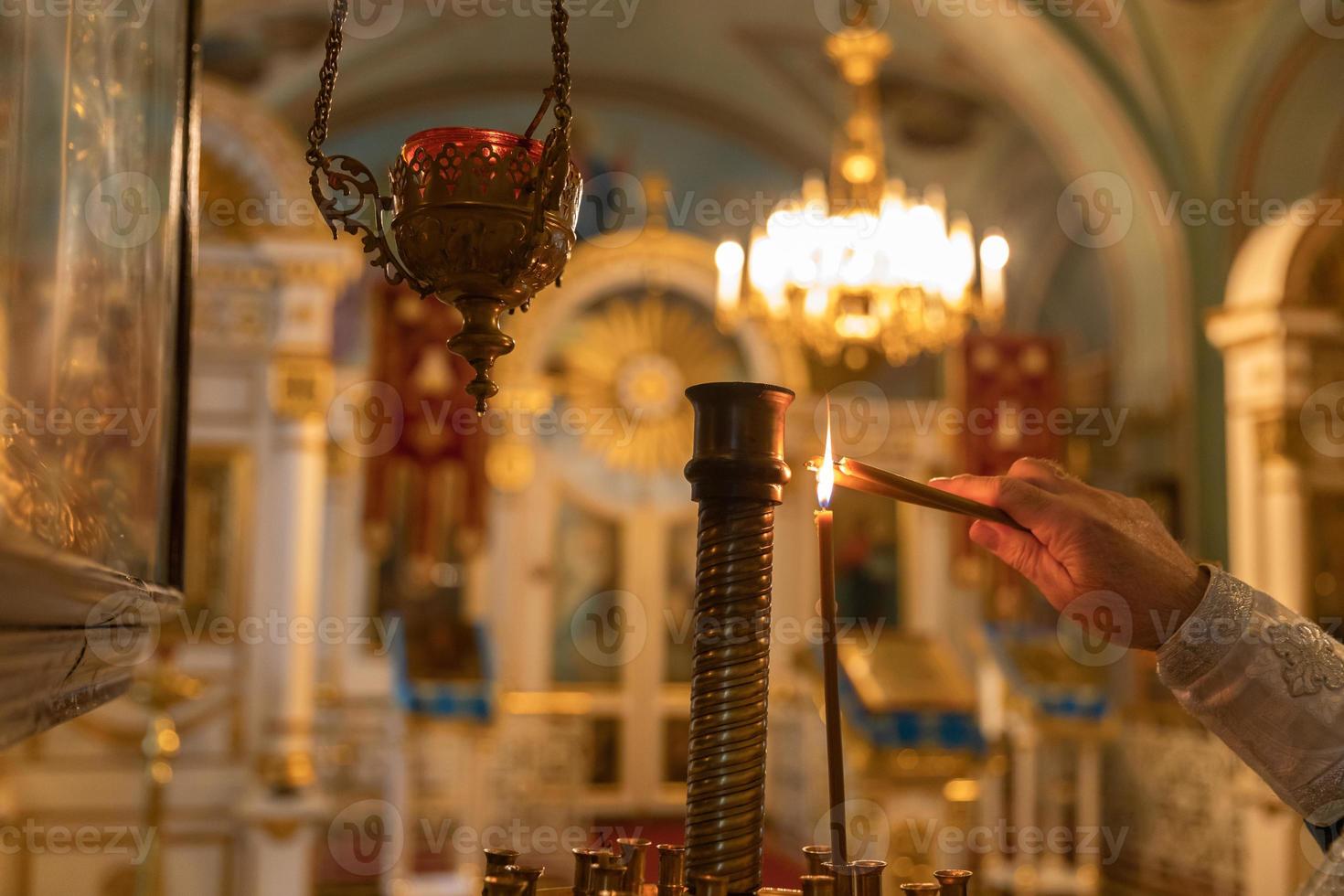 Chiesa ortodossa. cristianesimo. mano del sacerdote che accende candele accese nella tradizionale chiesa ortodossa alla vigilia di Pasqua o a Natale. religione fede pregare simbolo. foto